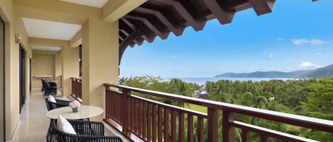 A balcony with a view of a tropical landscape, including palm trees and mountains.
