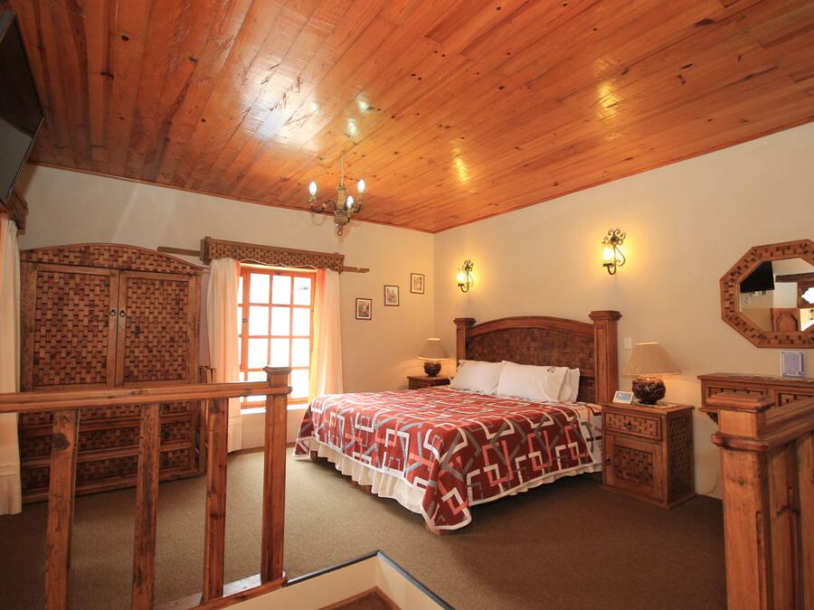 A wooden-paneled bedroom with a bed, nightstands, a dresser, and a mirror.