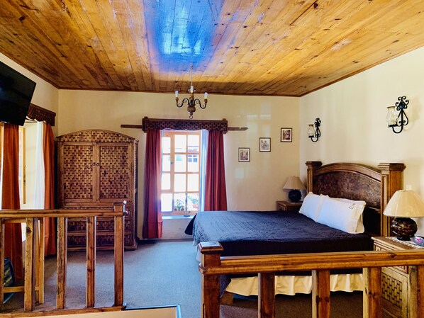 Un dormitorio con paneles de madera, una cama, un armario de madera, un escritorio y una araña.