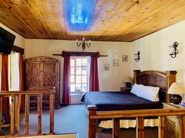 Une chambre aux murs lambrissés, avec un lit, une armoire en bois, un bureau et un lustre.