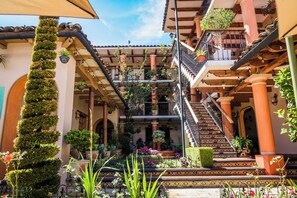 A multi-level courtyard with balconies, potted plants, and a staircase. - Hotel La Casa de Mama (San Cristóbal de las Casas)