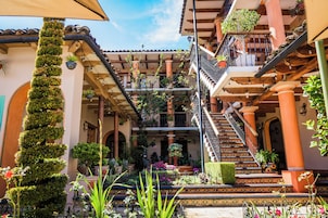 Un patio de varios niveles con balcones, plantas en macetas y una escalera.