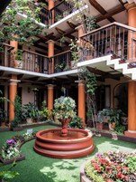 A multi-level atrium with balconies, a central fountain, and various potted plants.