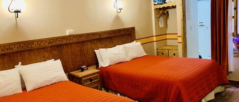A hotel room with two beds, wooden headboards, and a wooden ceiling.