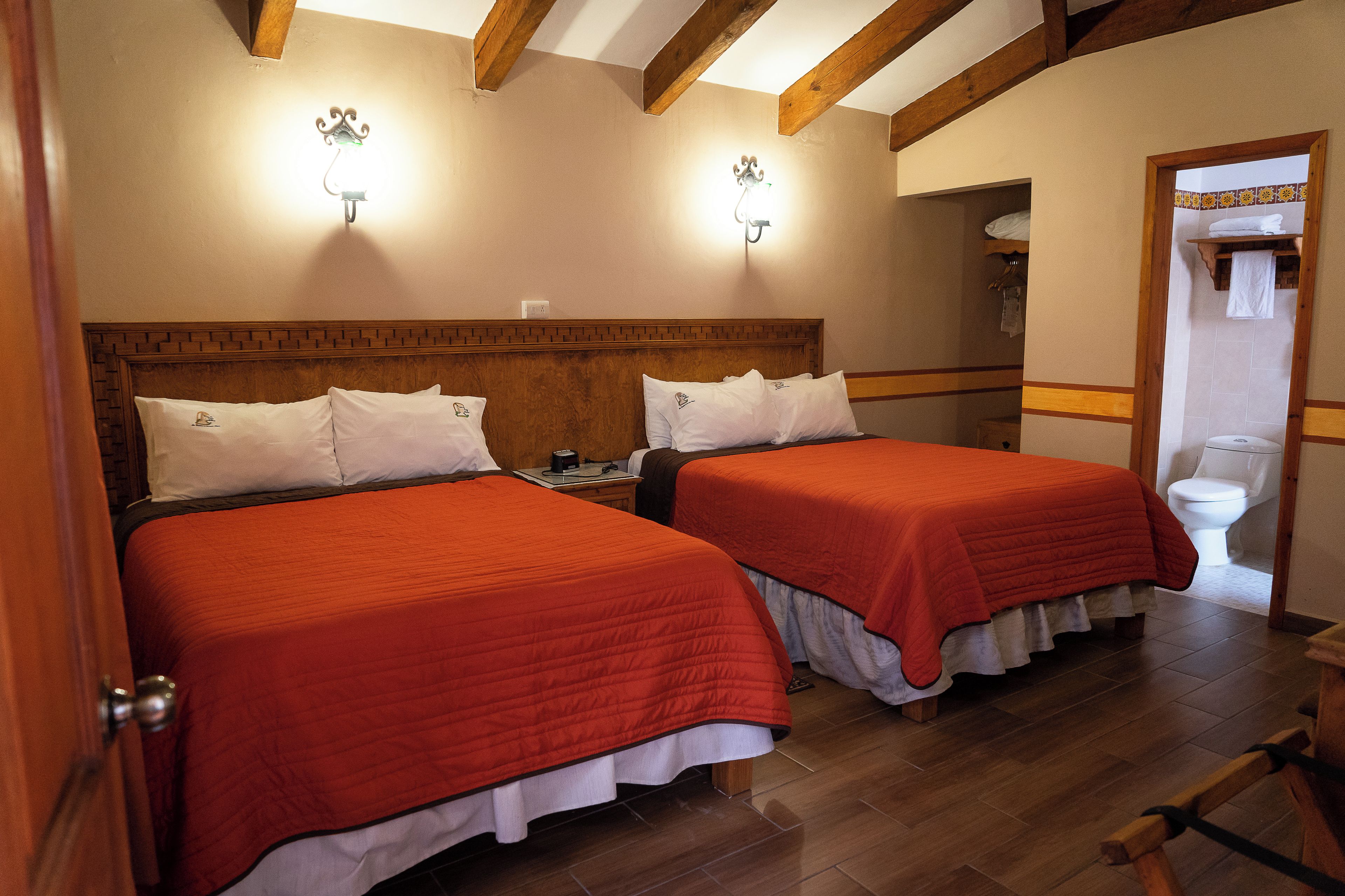 A hotel room with two beds, wooden headboards, and a wooden floor.