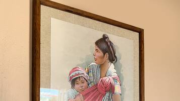A framed artwork of a woman holding a child in a sling, mounted on a wall.
