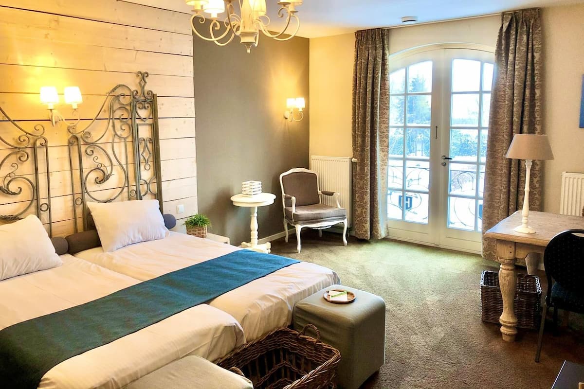 Habitación de hotel con una cama grande, un escritorio, una silla y una ventana con cortinas.
