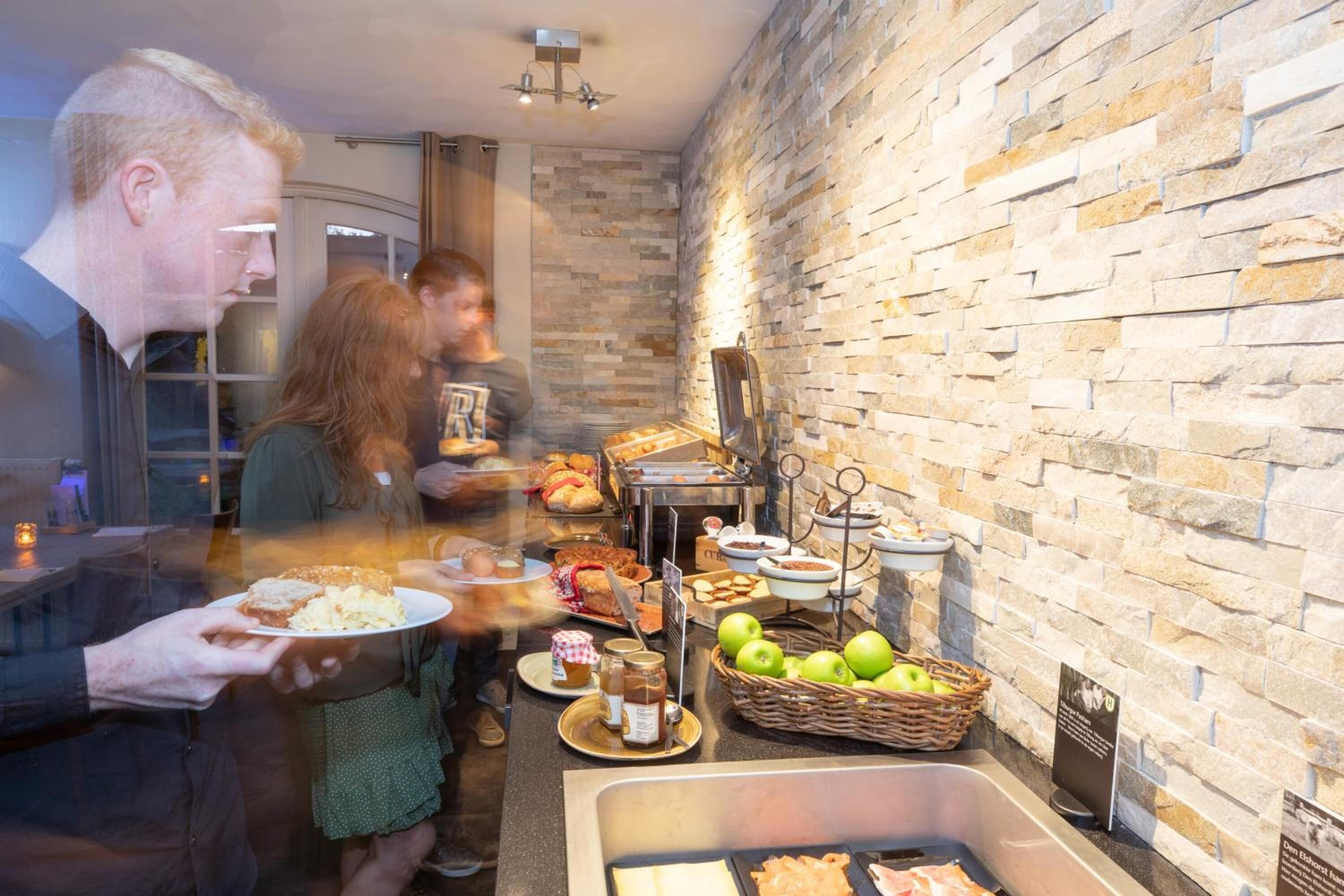Un bufé con diversos alimentos y una pared de piedra al fondo.