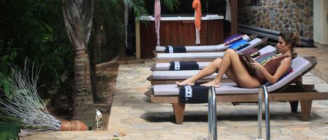 Una piscina al aire libre, sillones reclinables de piscina