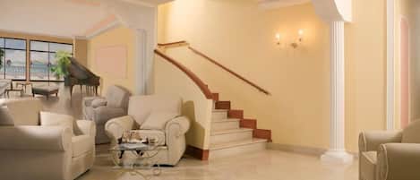 Un salón amplio con una imponente escalera, un piano y vistas al exterior.