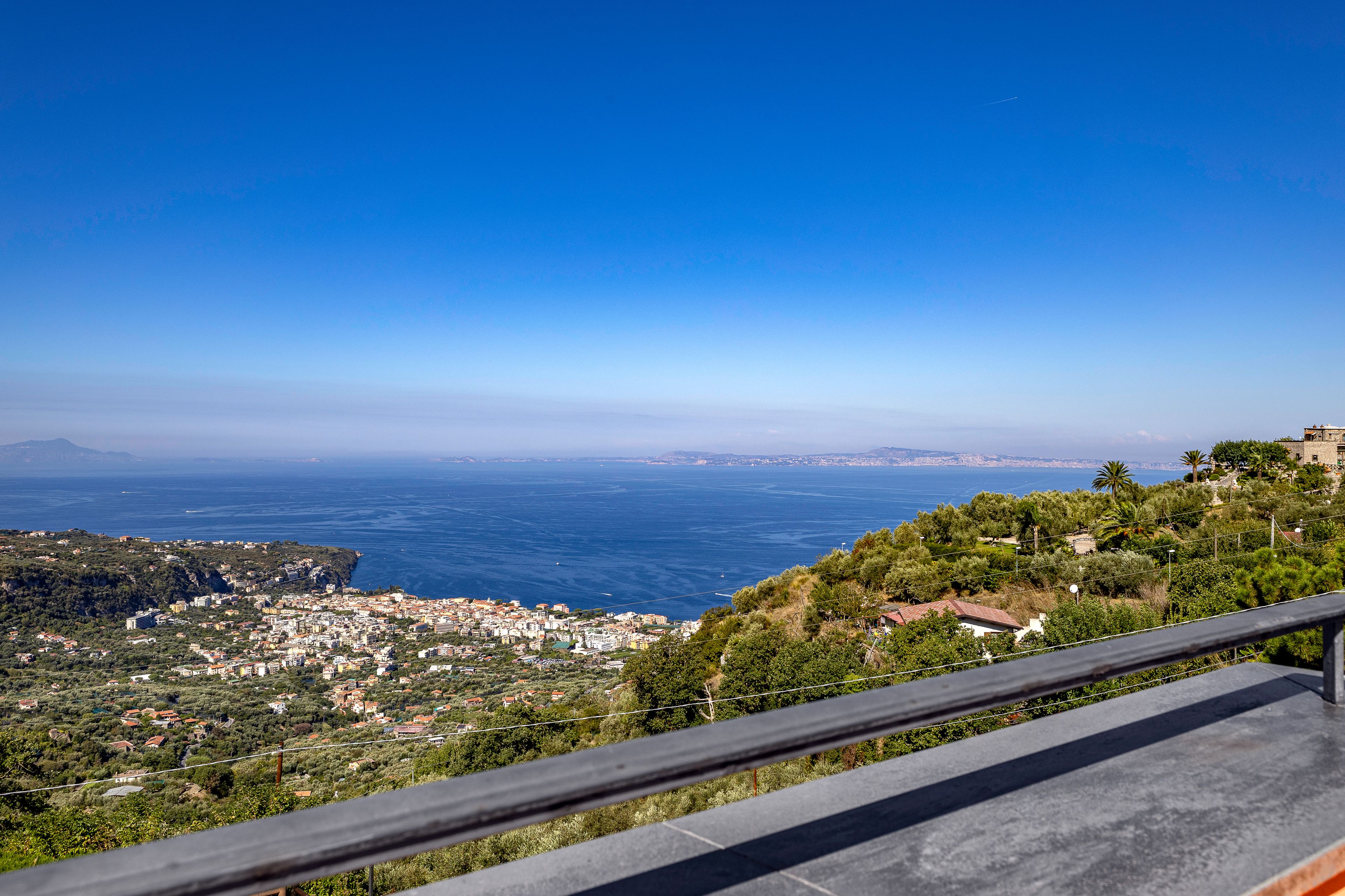 A coastal cityscape with a clear view of the sea and distant mountains.