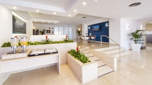 Un vestíbulo moderno con mostrador de recepción, zona de estar y una escalera que conduce a pisos superiores.
