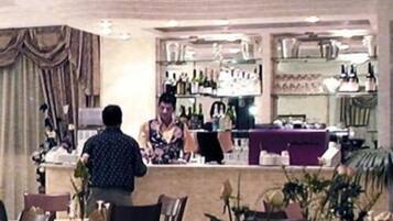 A restaurant interior with tables, chairs, a bar area, and shelves with bottles.
