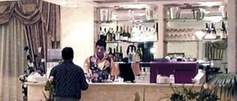 L’intérieur d’un restaurant, avec des tables, des chaises, un comptoir et des étagères remplies de bouteilles.