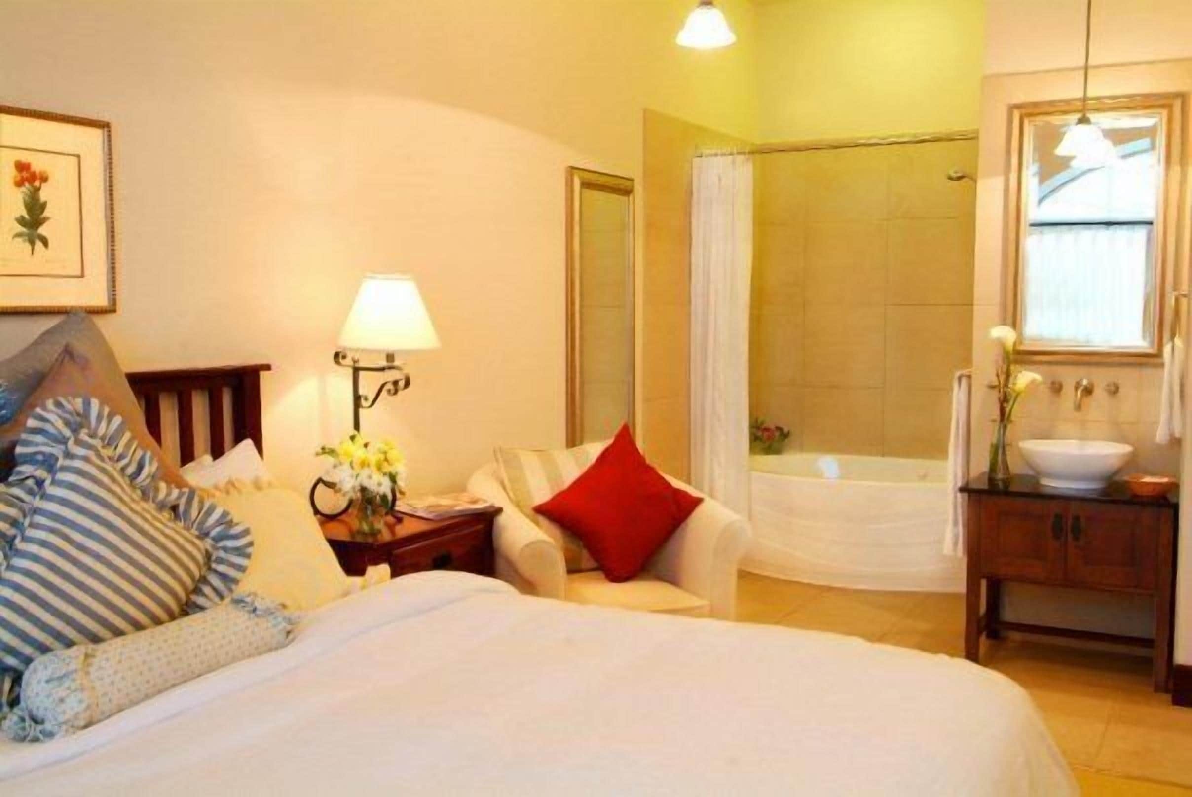 Camera d'albergo con un letto, un comodino, una sedia, un bagno con una vasca e una finestra.