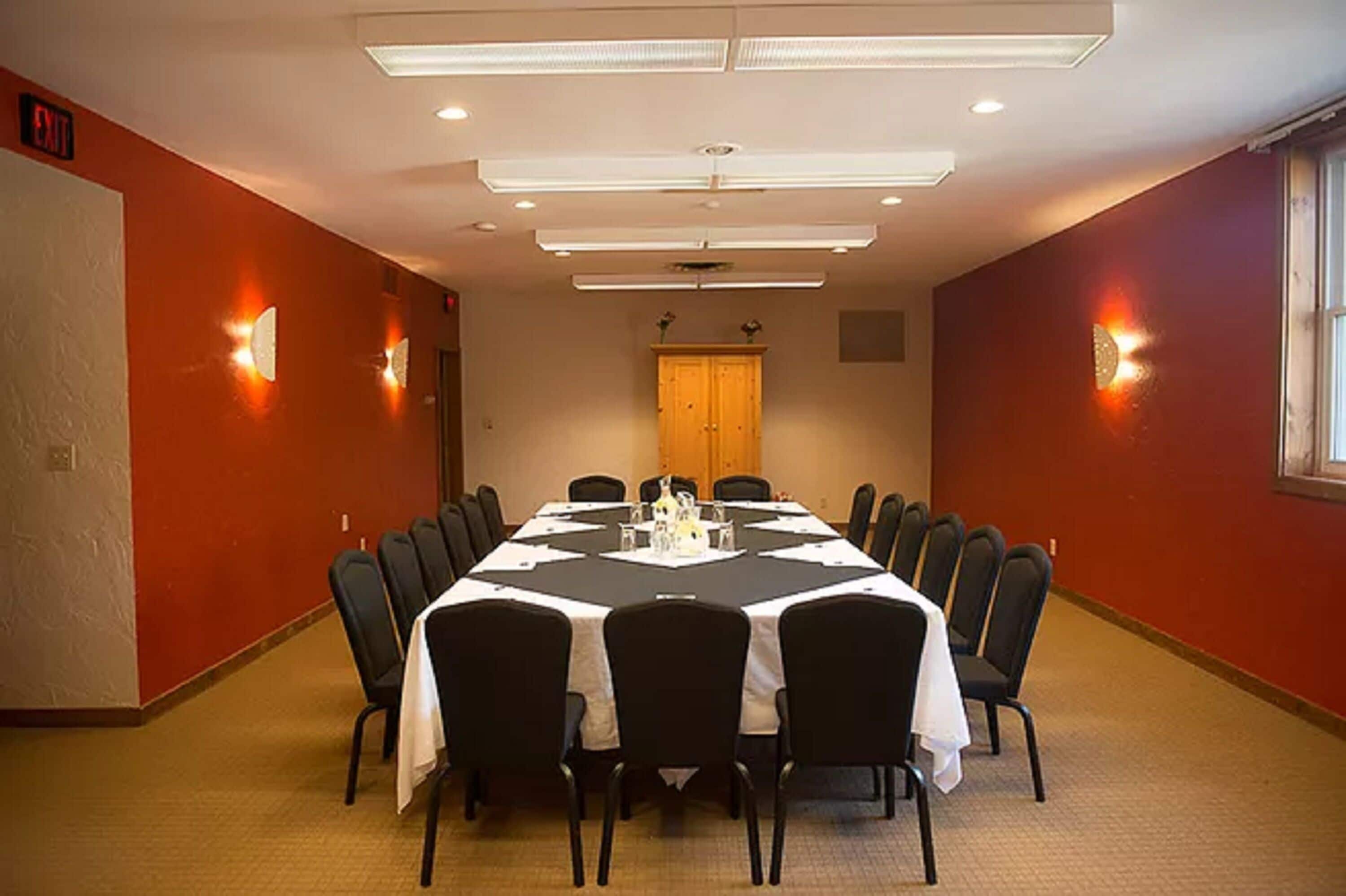 A conference room with a long table, chairs, and a wooden cabinet.