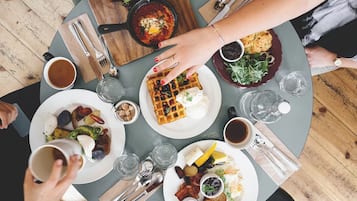 Una mesa redonda con diversos alimentos para el desayuno, como waffles, huevos y café.