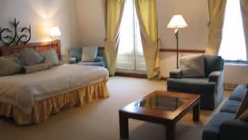 Habitación de hotel con cama, sofá, sillón, mesita de centro y dos lámparas.