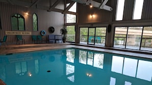 Une piscine intérieure dotée d’une signalisation claire, d’un décor en bois et offrant une vue sur l’extérieur.