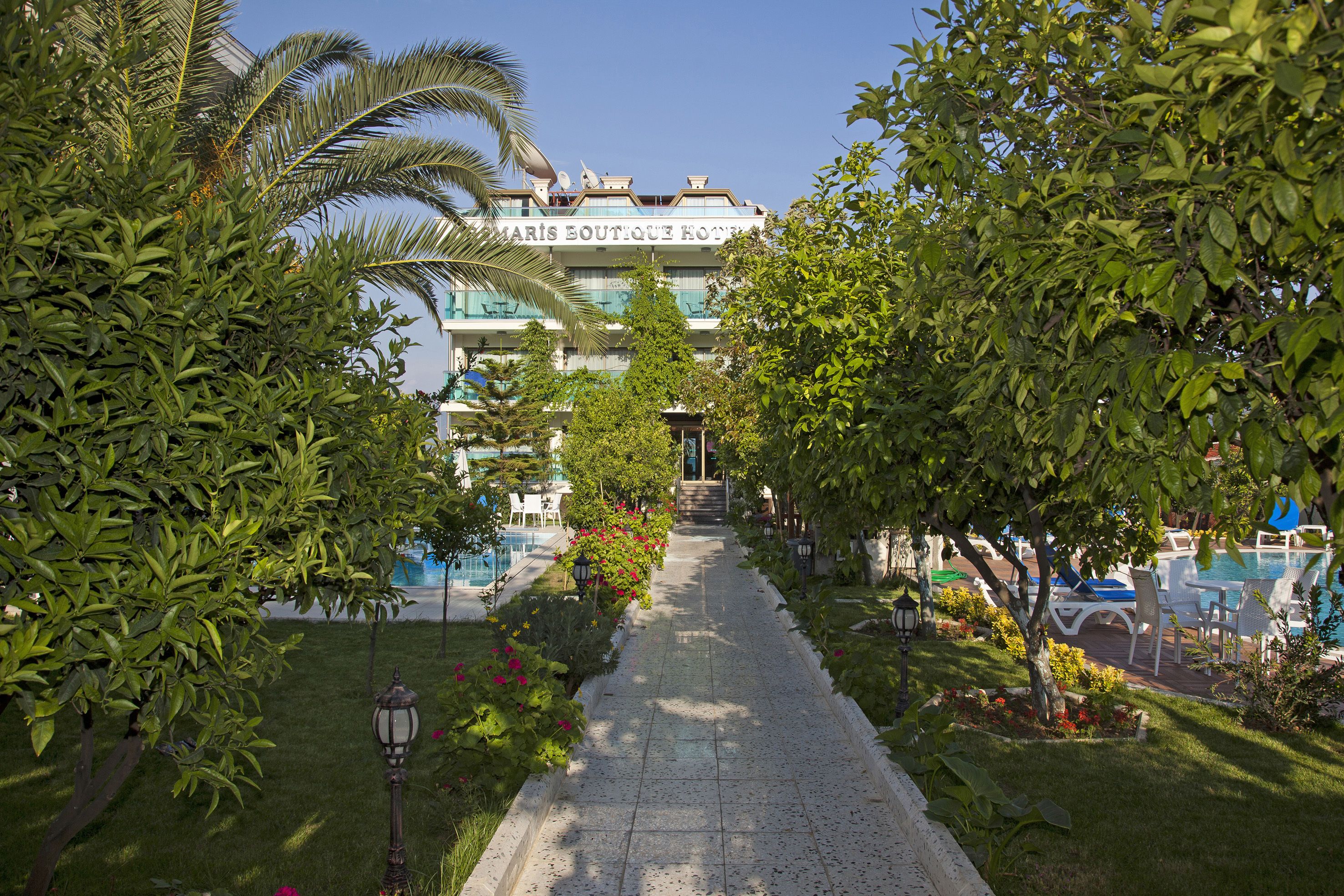 A pathway leading to a building with a sign reading "MARIS BOUTIQUE HOTEL".