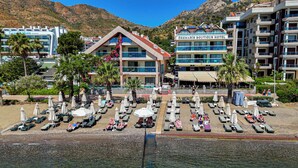 A hotel with multiple floors, outdoor seating with umbrellas, and a pool area. - Orsmaris Boutique Hotel - Boutique Class (Marmaris)