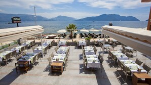 An outdoor dining area with tables and chairs arranged for guests, overlooking a body of water and mountains. - Orsmaris Boutique Hotel - Boutique Class (Marmaris)