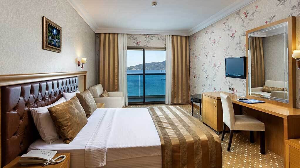 Habitació d'hotel amb un llit, escriptori, cadira, televisió i vista al mar.