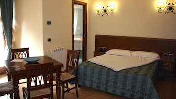Une chambre avec un lit en bois, une table de chevet, une commode, une chaise, une table avec un bol, et deux lampes fixées au mur.