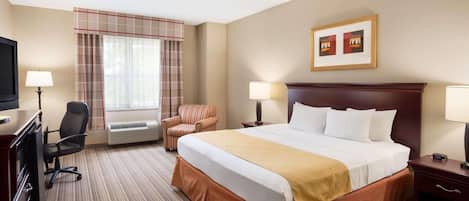 A hotel room with a large bed, two bedside tables, a desk with a chair, a television, and a window with curtains.