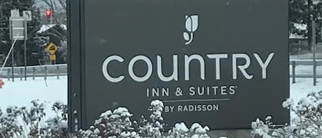A sign for Country Inn & Suites by Radisson, featuring a modern design with a logo and name prominently displayed.