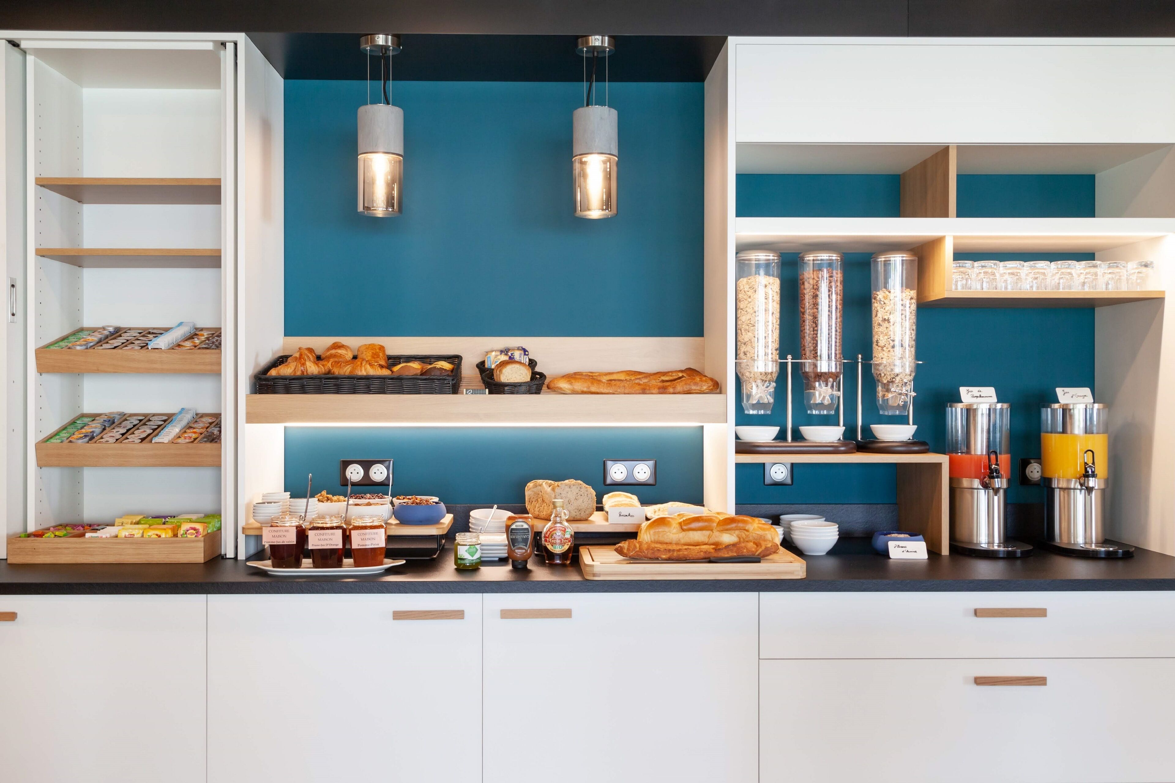 Una barra de desayuno con diversos alimentos, frascos de condimentos y máquinas de café.