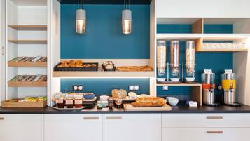 Una barra de desayuno con diversos alimentos, frascos de condimentos y máquinas de café.