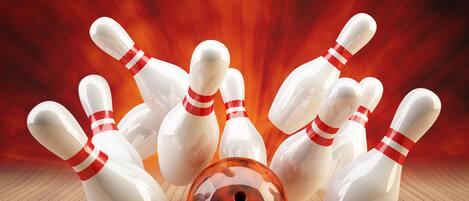 A bowling alley with multiple pins and a bowling ball in motion.