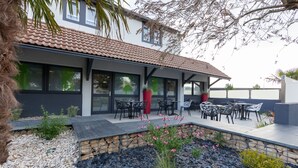 Un patio cubierto con mobiliario exterior, un muro de contención de piedra y una planta en maceta.
