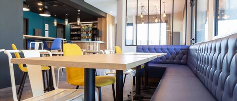Um restaurante moderno com área de bar, disposição de assentos e vista pela janela ampla.