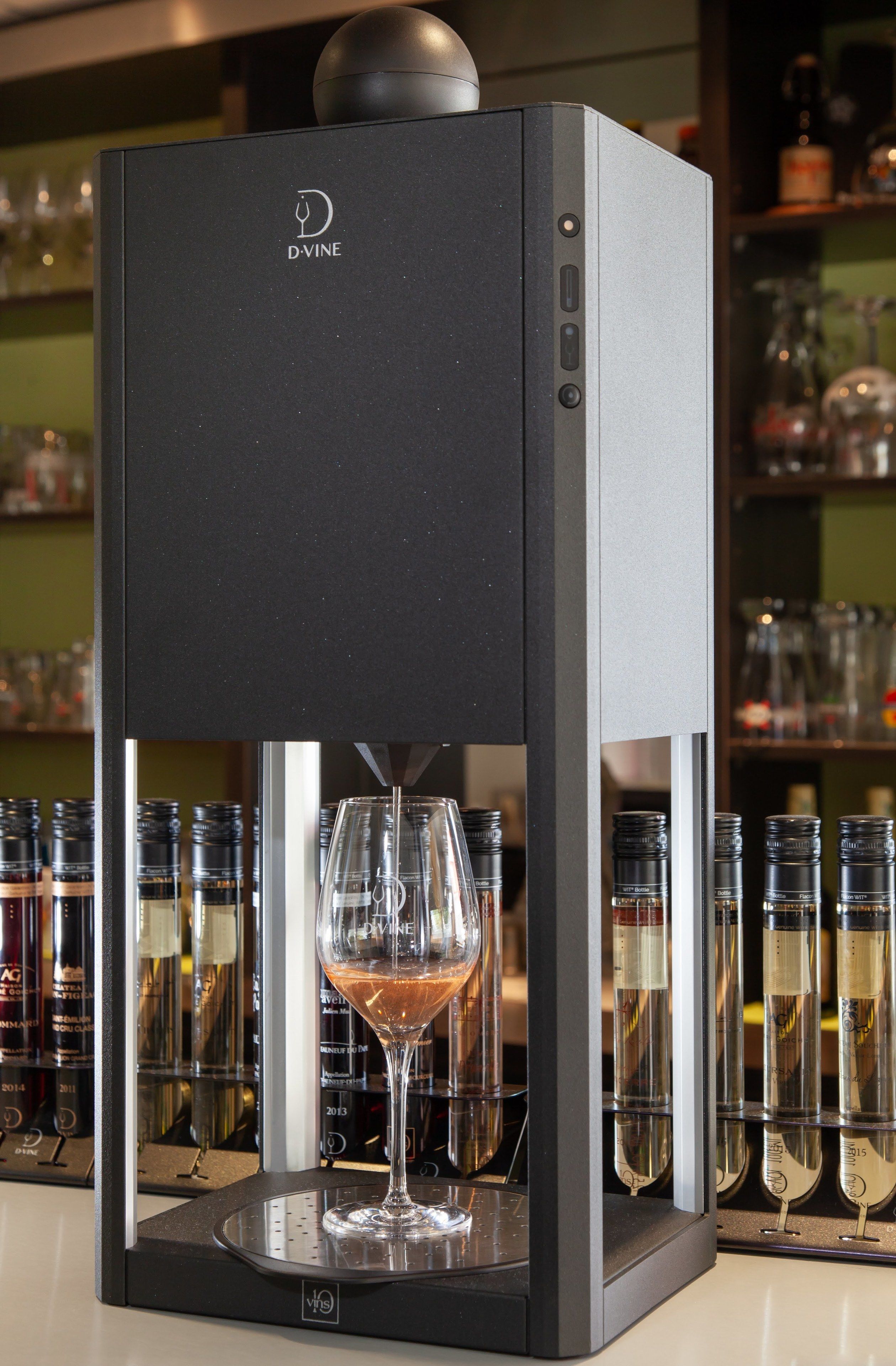 A D-VINE wine dispenser with a wine glass in front of it.