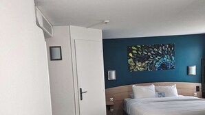 Una habitación de hotel con cama, armario y un escritorio pequeño.