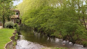 Un río que atraviesa un parque con un edificio sobre pilares.