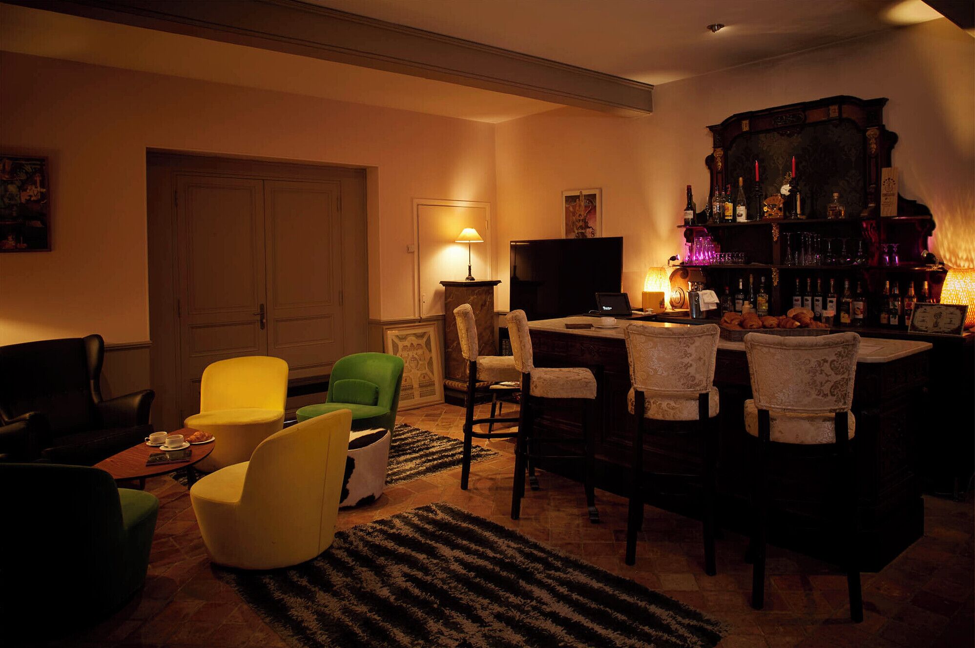 A cozy living room with a fireplace, a television, and a bar area with bottles and glasses.