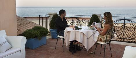 Una terraza con una mesa lista para dos, con vista al mar.