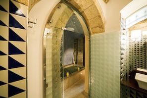 Un baño con cabina de ducha de vidrio, paredes con azulejos y zona de lavamanos.