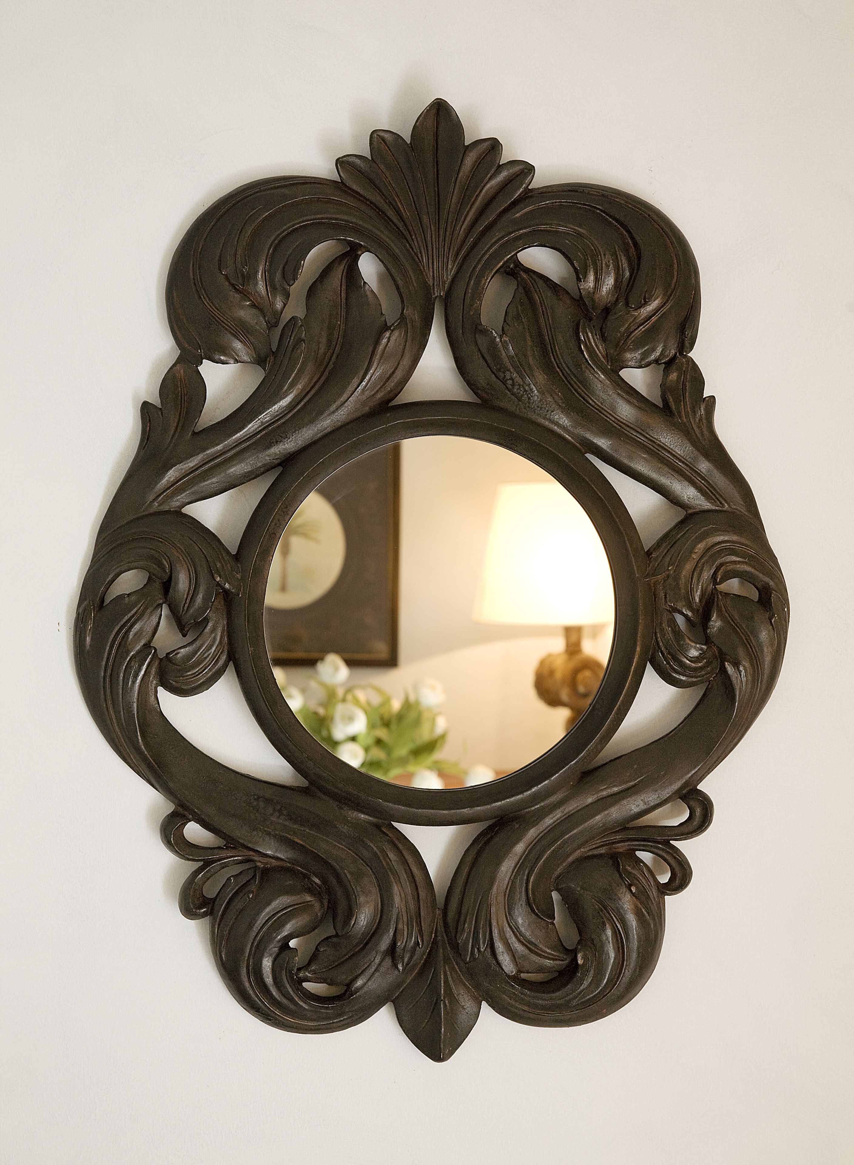A dark ornate mirror with a circular frame.