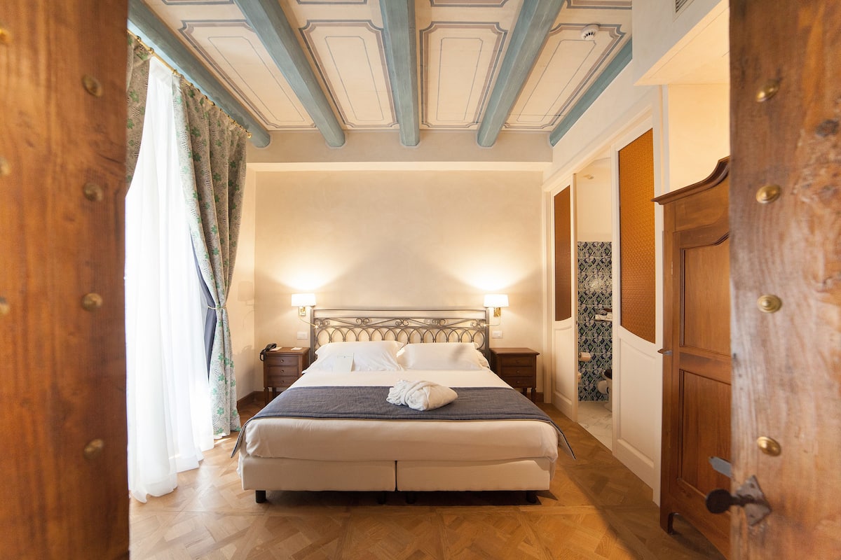 Un dormitorio con una cama grande, armario de madera y techo con molduras decorativas.