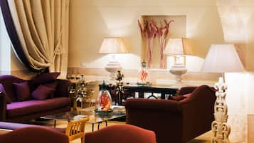 Un salon comprenant un canapé, des fauteuils, une table basse et des lampes.