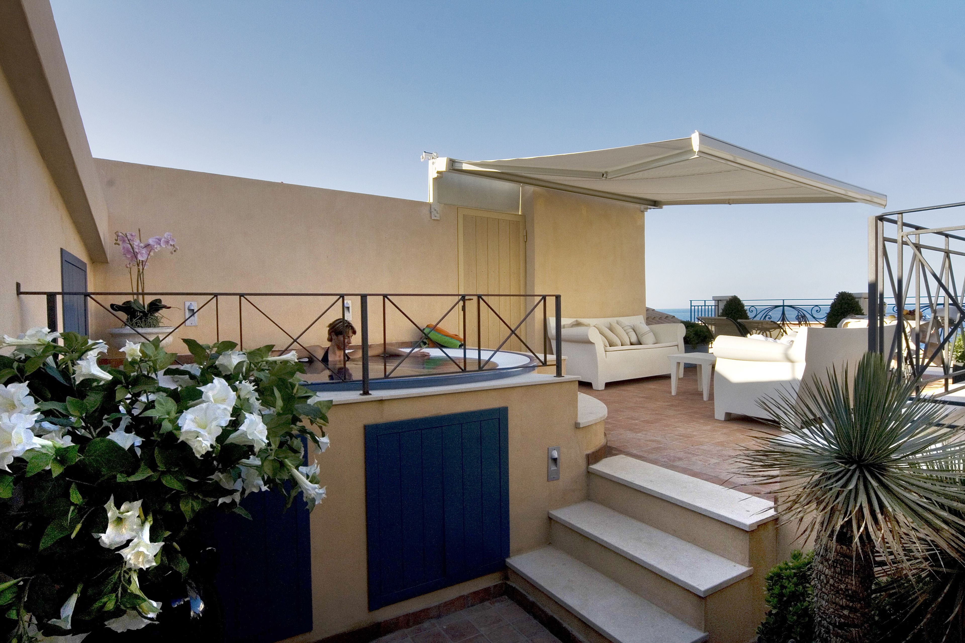 A rooftop terrace with outdoor seating, a hot tub, and a view of the sea.