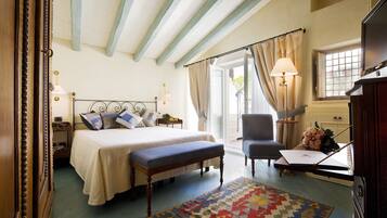 A bedroom with a bed, bedside table, chair, desk, lamp, and a view of the outdoors.