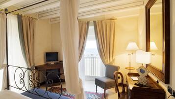 Une chambre d’hôtel avec un lit, un bureau avec une télévision, une chaise, une lampe et un grand miroir.