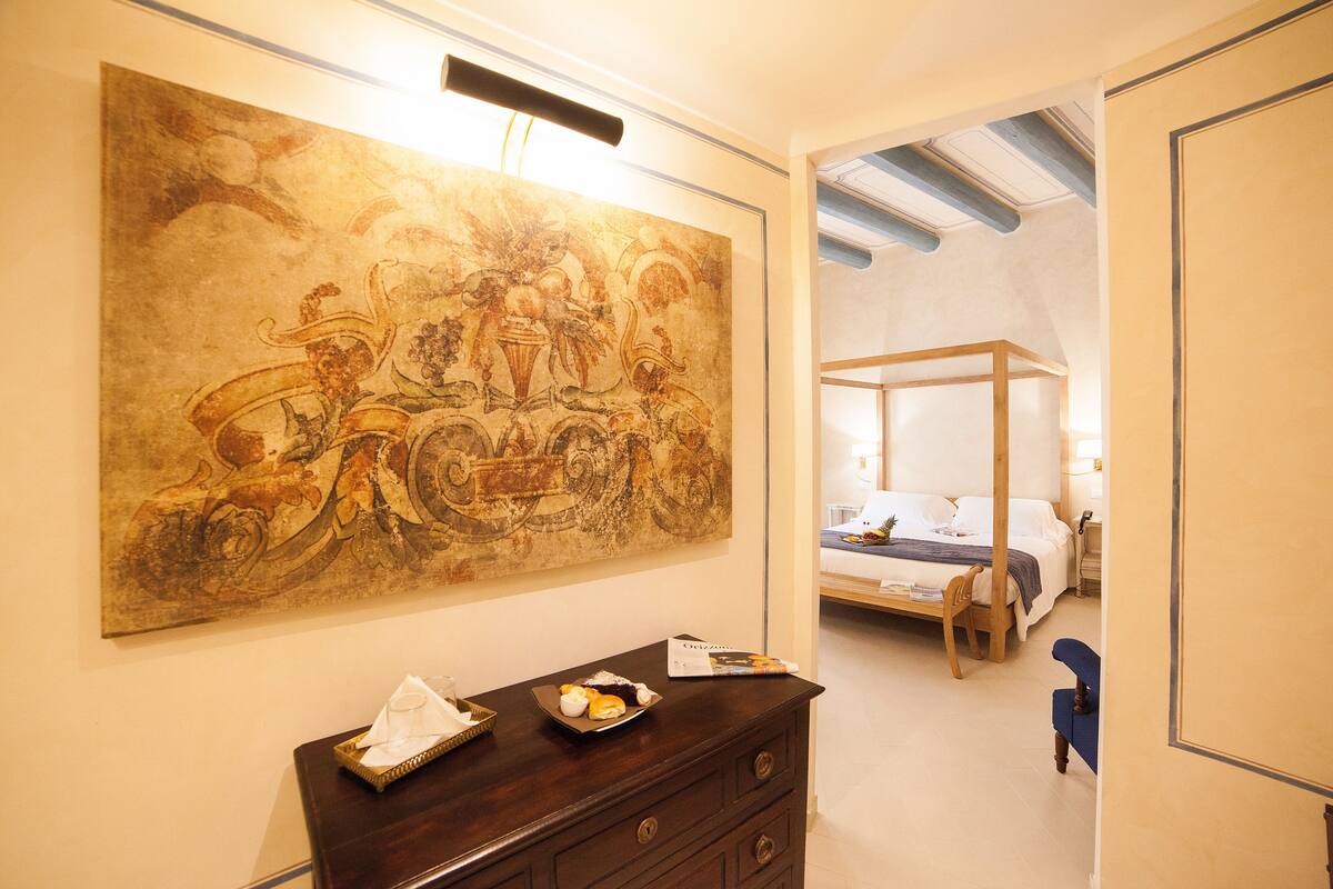Un dormitorio con un cuadro grande, un aparador de madera y una cama con dosel.