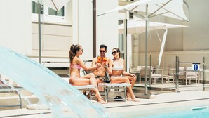 A poolside area with lounge chairs, umbrellas, and a water slide.