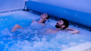 Dos personas relajándose en un jacuzzi con interior azul.
